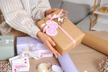 Hediye kutuları, ambalaj kağıtları ve tahta masada tebrik kartları olan kadın elleri. Uluslararası Kadınlar Günü