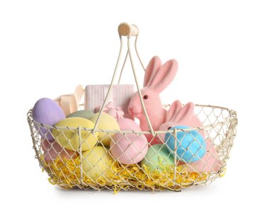 İçinde boyanmış Paskalya yumurtaları, oyuncak tavşanlar ve beyaz arka planda hediye kutusu olan sepet.