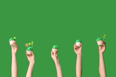 Yeşil arka planda Aziz Patrick Günü için lezzetli kekleri olan kadın eller.
