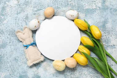 Boyanmış Paskalya yumurtaları, lale çiçekleri ve mavi grunge arka planda oyuncak tavşanı olan boş bir kart.