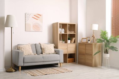 Rahat kanepesi, çiçekleri, resmi ve rafları olan modern oturma odasının içinde.