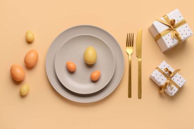 Turuncu arka planda hediyeler ve yumurtalarla güzel bir Paskalya masası.