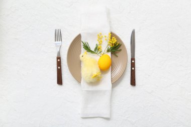 Beyaz arka planda boyanmış yumurta, civciv ve mimoza ile Paskalya kutlaması için şık bir masa.