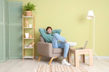 Evdeki yumuşak koltukta dinlenen yakışıklı adam.