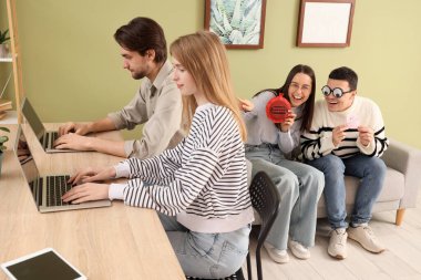 Osuruk yastıklı genç meslektaşlar ofiste eşek şakası yapmayı planlıyor. 1 Nisan Kutlaması