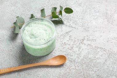 Arka planda vücut fırçası, kaşık ve okaliptüs dalıyla dolu kavanoz.