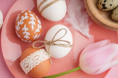 Pembe arka planda Paskalya yumurtası ve lale tabağı, yakın plan.