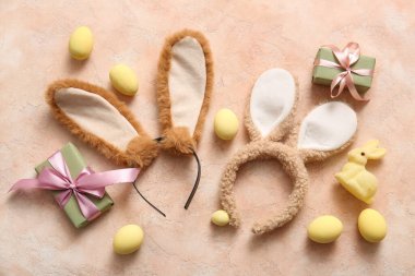 Paskalya yumurtalı tavşan kulakları ve bej renkli grunge arka planda hediye kutuları.