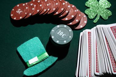 Poker fişleri, kartlar, leprikon şapkası ve koyu yeşil arka planda şanslı yonca. Aziz Patrick Günü kutlaması