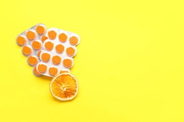 Ağrıyan boğaz için haplar, sarı arka planda kuru turuncu dilimler.