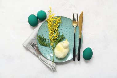 Paskalya kutlaması için şık bir masa. Beyaz arka planda Paskalya yumurtaları, civciv ve mimoza.