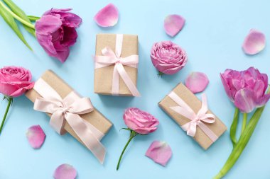 Şirin hediye kutuları ve cyan arka planda çiçekleri olan kompozisyon