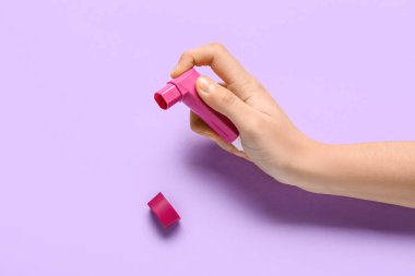 Leylak arka planında astım spreyi olan bir çocuk eli.