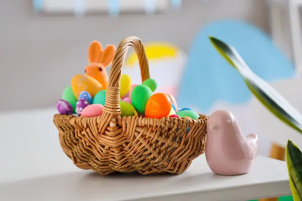 Easter basket with ceramic bird on table in room