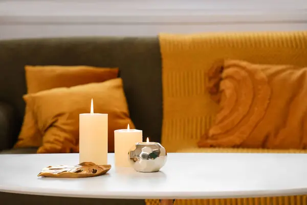 Burning candles on table in stylish living room, closeup