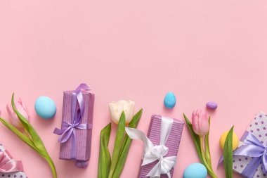 Lale çiçekli Paskalya yumurtaları ve pembe arka planda hediye kutuları.