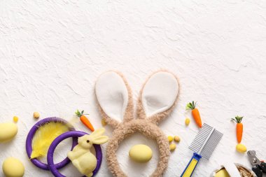 Paskalya yumurtalı tavşan kulakları ve beyaz grunge arka planda evcil hayvan bakım aletleri.