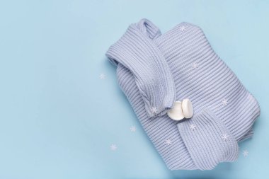 Süslü kar taneleriyle bir kavanoz krema ve mavi arka planda sıcak kış süveteri.