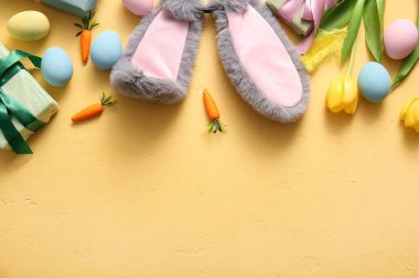 Paskalya yumurtası, havuç ve sarı arka planda hediye kutuları olan tavşan kulakları.
