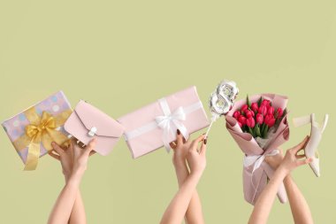 Bir buket lale, hediye kutuları ve yeşil arka planda el çantası olan kadın elleri. Uluslararası Kadınlar Günü için Alışveriş