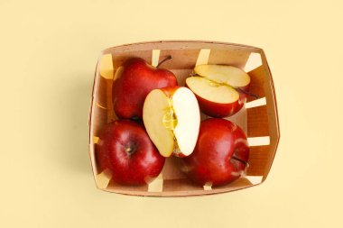 Sarı arka planda taze kırmızı elmalı sepet.