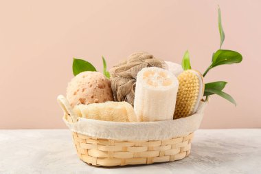 Pembe duvarın yanındaki sepetteki süngerler. Banyo aksesuarları