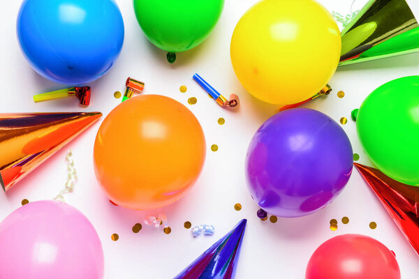 Balloons, party hats, confetti and party horns on white background