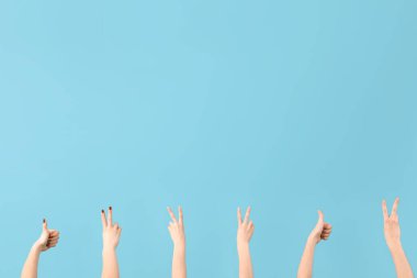 Mavi arka planda barış ve başparmak hareketi gösteren kadın elleri