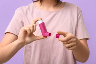 Leylak arka planında astım spreyi olan çocuk, yakın plan.