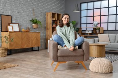 Mutlu genç kadın evde koltukta oturuyordu