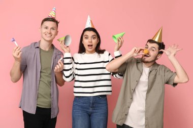 Parti konileri ve pembe arka planda ıslıklarla kılık değiştirmiş genç şok olmuş arkadaşlar. 1 Nisan kutlamaları