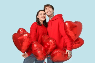 Young couple with heart-shaped air balloons on blue background. Valentine's day celebration