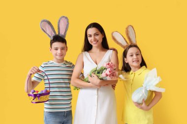 Paskalya yumurtaları ve sarı arka planda laleleri olan tavşan kulaklı mutlu bir aile.