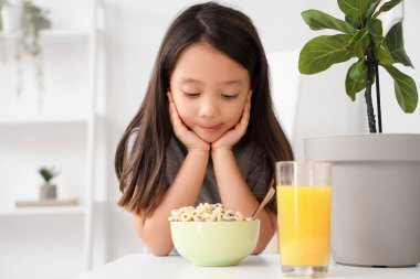 Evdeki masada bir kase mısır gevreği yüzüğüyle sevimli bir Asyalı kız.