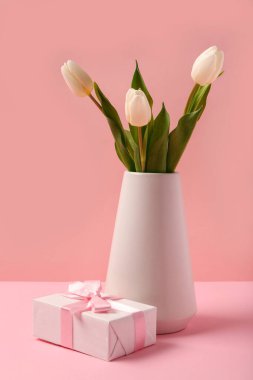 Güzel beyaz laleli vazo ve pembe arka planda hediye kutusu. Uluslararası Kadınlar Günü