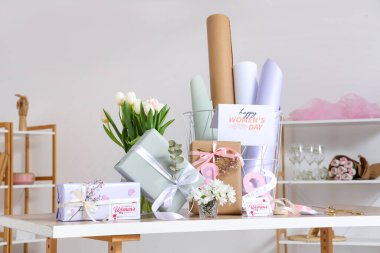 Gri duvara karşı Uluslararası Kadınlar Günü için güzel hediye kutuları, paketleme malzemeleri ve çiçekler.