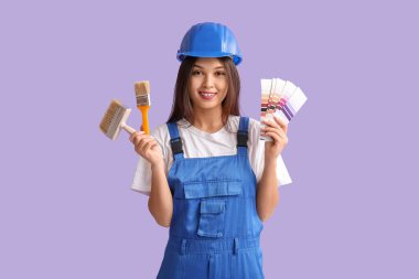 Leylak arka planında fırça ve renk örnekleri olan genç bir kadın ressam.