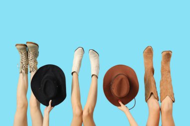 Mavi arka planda farklı çizmeleri ve şapkaları olan şık kadınlar.