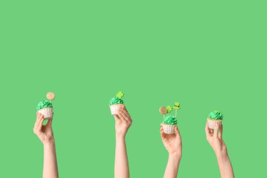 Yeşil arka planda Aziz Patrick Günü için lezzetli kekleri olan kadın eller.