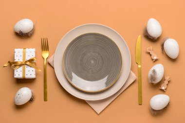 Bej arka planda yumurtalar ve hediyelerle süslü Paskalya sofrası.