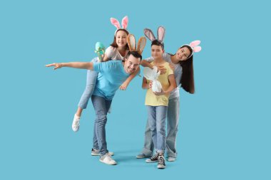 Mavi arka planda Paskalya yumurtaları olan tavşan kulaklı mutlu bir aile.