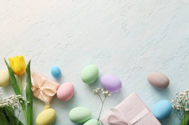 Çiçekli boyanmış Paskalya yumurtaları ve mavi grunge arka planda hediye kutuları.