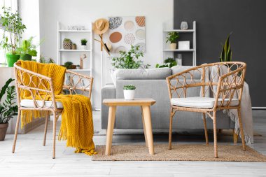 Koltukları, gri kanepesi ve çiçekleri olan modern oturma odasının içinde.