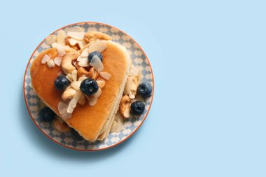 Kalp şeklinde lezzetli krepler, mavi arka planda yabanmersini ve fındıklı. Sevgililer Günü kutlaması