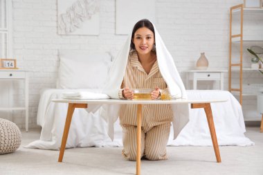 Genç Asyalı kadın yatak odasındaki masada buhar solunumu yapıyor.