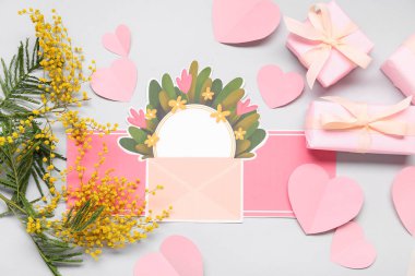 Beyaz zemin üzerinde boş kart, mimoza ve hediye kutuları olan kompozisyon