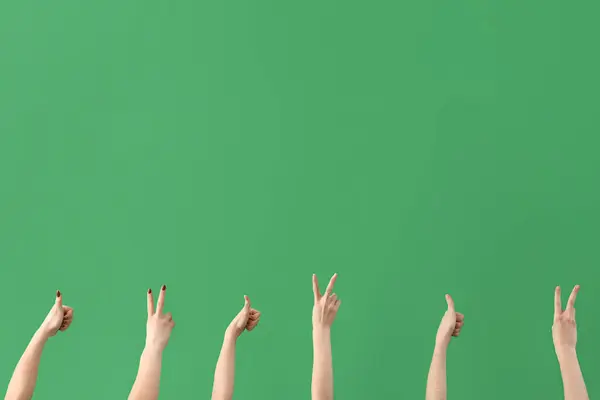 Female hands showing peace and thumb-up gestures on green background