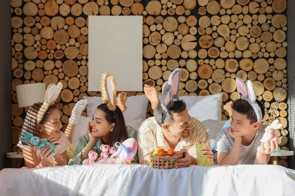 Happy family with painted eggs and rabbits lying in bedroom on Easter Day