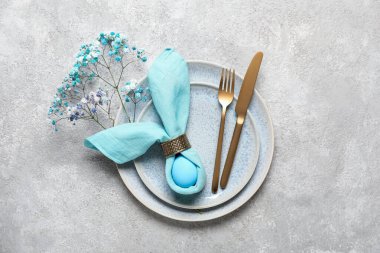 Paskalya için çok güzel bir sofra. Gri arka planda yumurta ve çiçekler var.