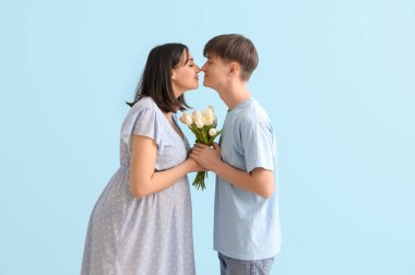 Mavi arka planda laleleri olan hamile bir çift.